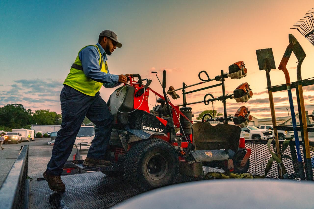 Lawn care professional in workwear loading commercial equipment